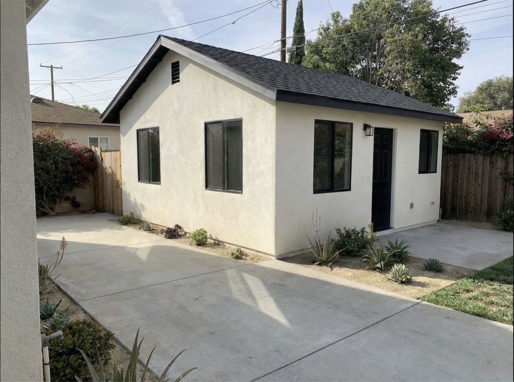 Completed garage conversion ADU with white stucco exterior and black-framed windows, built by YBL Design and Build