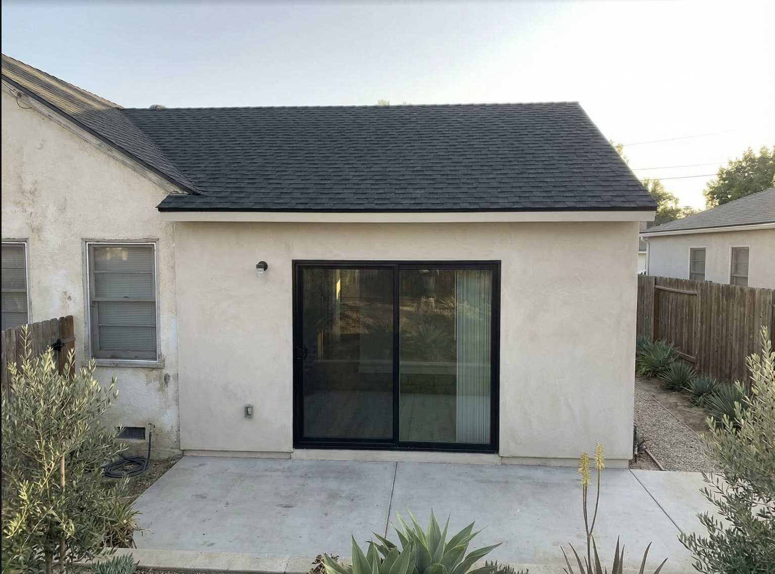 Room addition with large black-framed sliding glass doors connecting to the backyard in Los Angeles — YBL Design & Build
